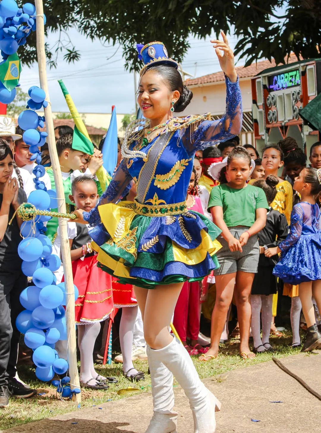 Baliza de figurino azul e amarelo ergue o braço durante desfile.