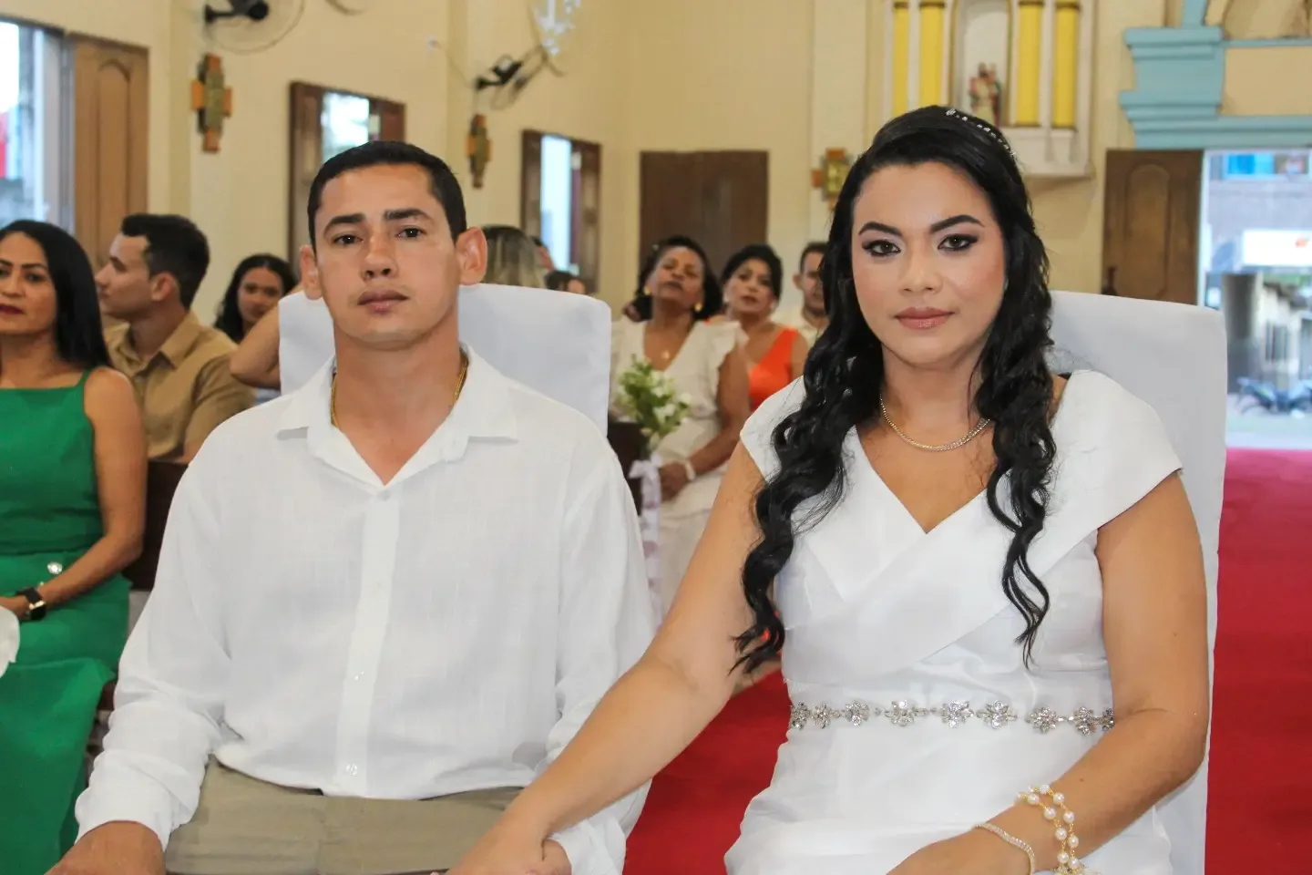 Noivos sentados lado a lado durante a cerimônia na igreja.